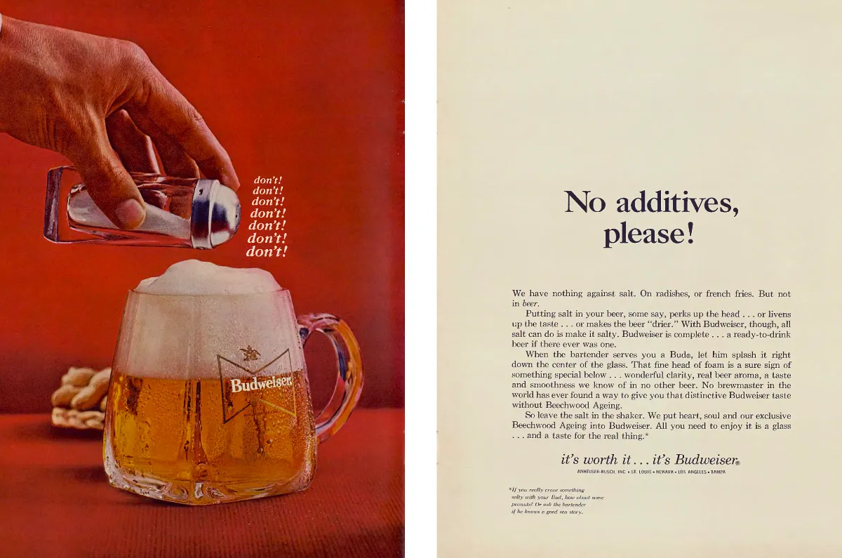 A salt shaker hovers over a foaming Budweiser mug on a red background beside a cream page of copy.
