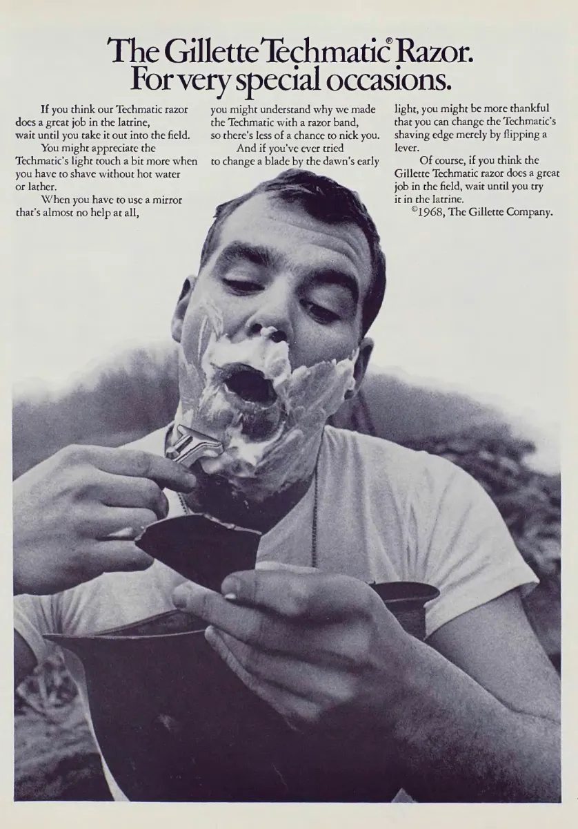 A man shaves outdoors with a Gillette Techmatic, holding a small mirror above a helmet, beneath three columns of copy.