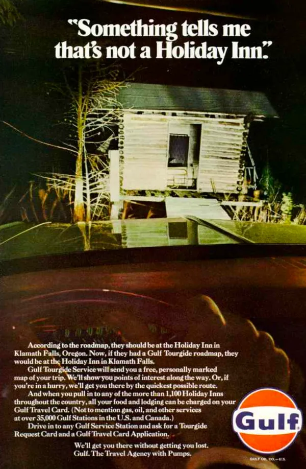 Headlights illuminate a rustic cabin at night from inside a car, under a line about reaching the wrong Holiday Inn.