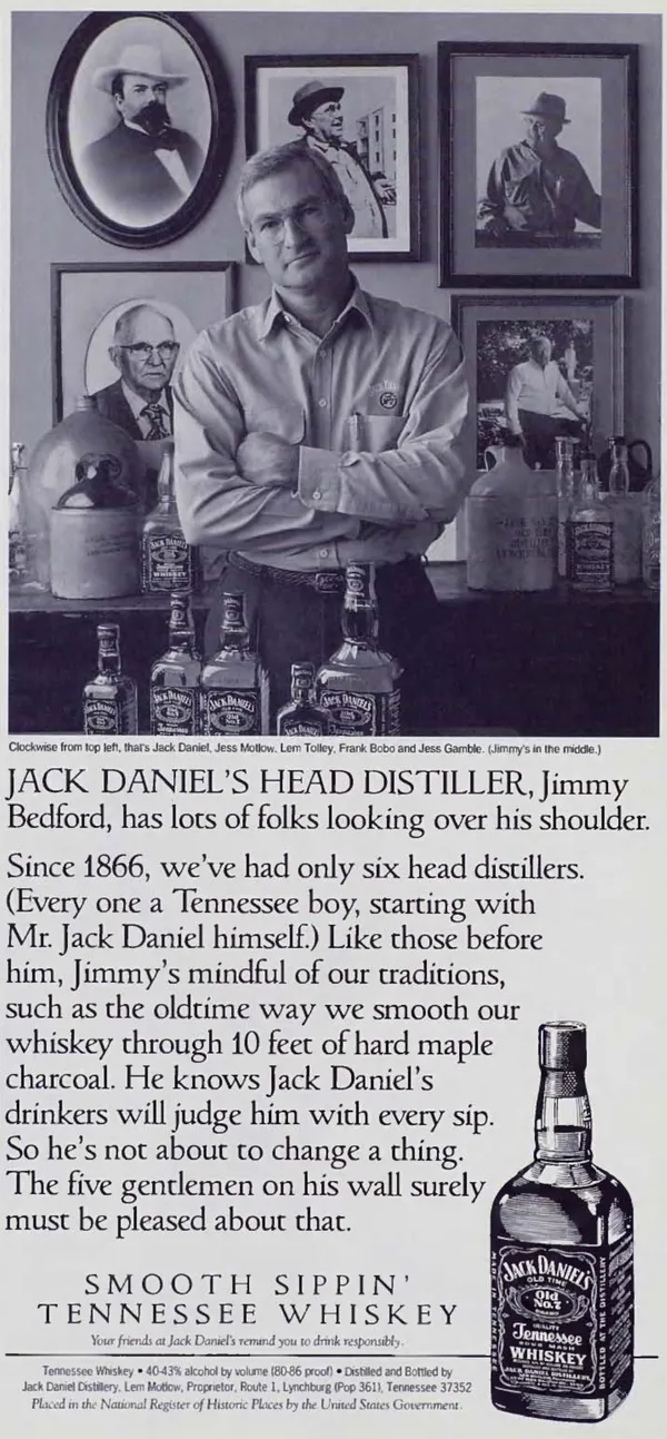 A Jack Daniel's head distiller standing among bottles and portraits of the distillery's previous leaders.