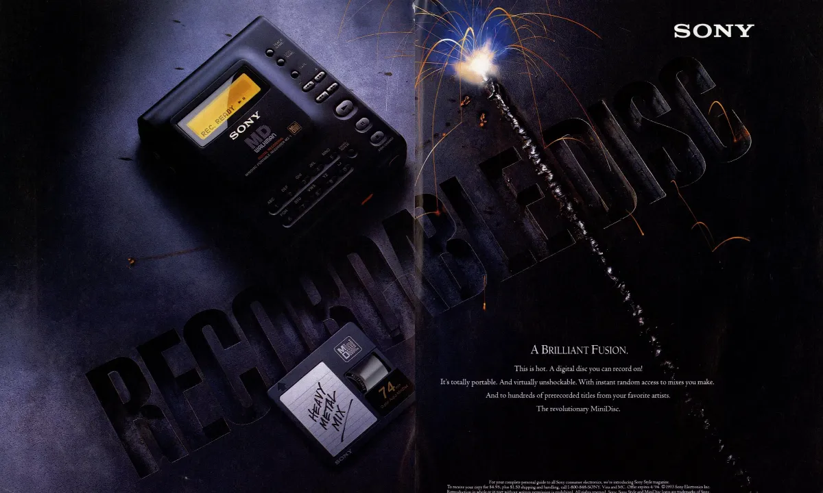 A Sony MiniDisc recorder and a handwritten mix disc sit against dark metal lettering and a bright welding spark.