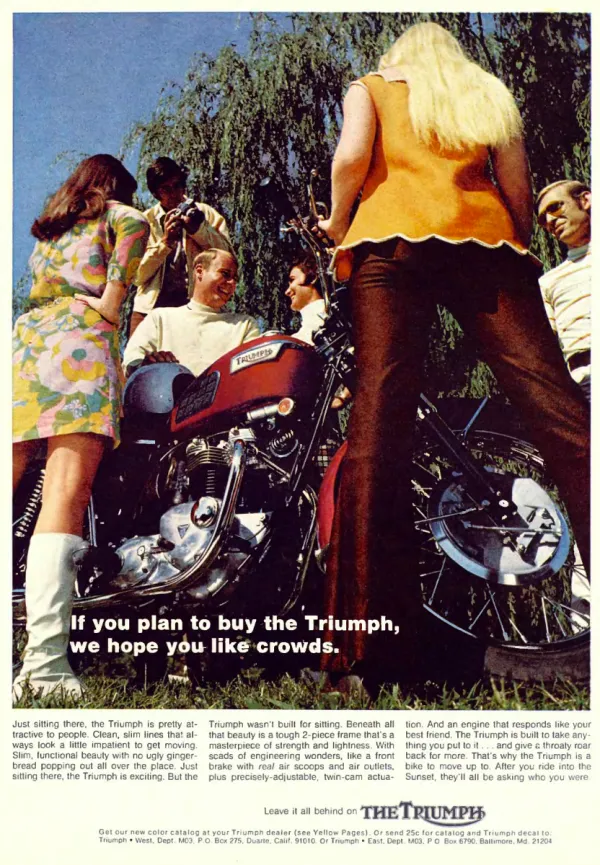 A Triumph motorcycle is surrounded by five admiring people in a color photograph, with its headline laid over the grass.