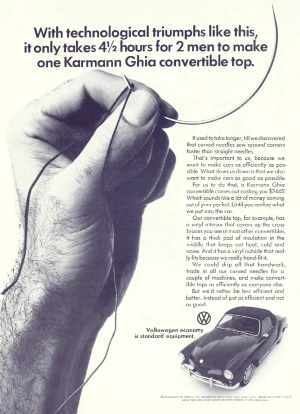 Large hand holds a curved sewing needle above a small photograph of a Volkswagen Karmann Ghia convertible.
